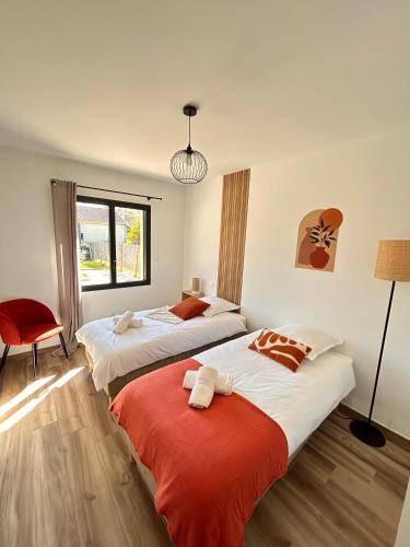 une chambre avec deux lits et une chaise rouge dans l'établissement Villa en Provence avec piscine, à Mollégès