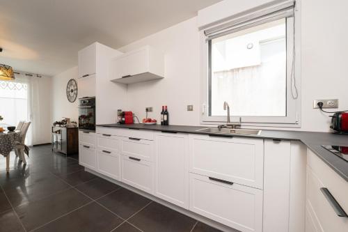 a white kitchen with a sink and a window at Ma Bro - ERDIVINES in Erdeven