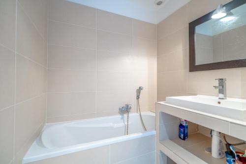 une salle de bain blanche avec un lavabo et une baignoire dans l'établissement Évasion en Méditerranée, à La Garonnette-Plage