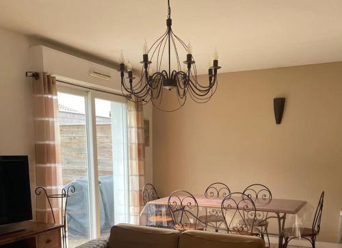 une salle à manger avec une table et un lustre dans l'établissement Maison pavillonnaire entre océan et montagnes basques, à Cambo-les-Bains