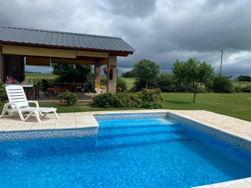 a swimming pool with a chair and a gazebo at Casa de Descanso. in Villa María