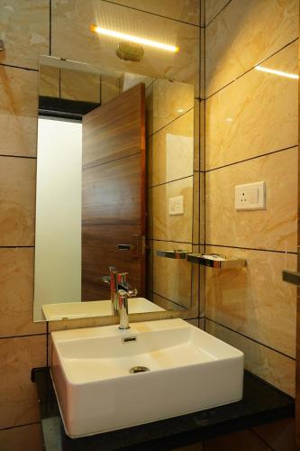 a bathroom with a white sink and a mirror at J S Grand in Yelagiri