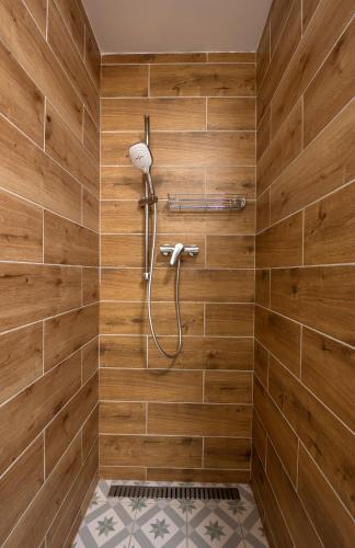 a bathroom with a shower with wooden walls at Apartmány Pernek in Horní Planá