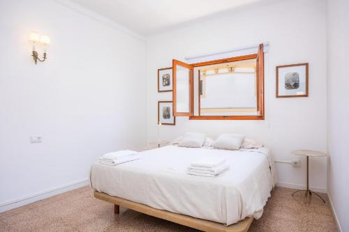 a white bedroom with a bed and a window at Can Manuel in Felanitx