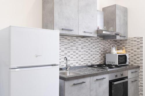 a kitchen with a white refrigerator and a sink at Cuore di Conchiglia 3 in Custonaci