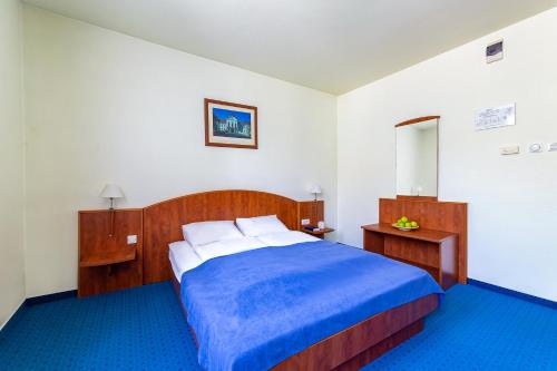 a bedroom with a bed with a blue blanket at Villa Oliver Gödöllő in Gödöllő