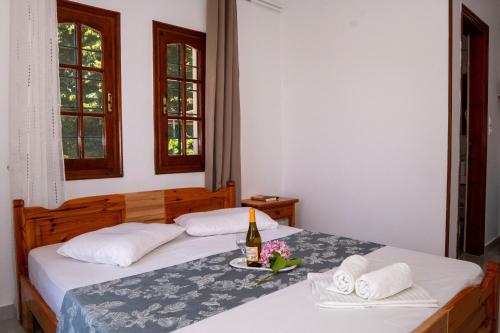 two beds in a room with a bottle of wine and towels at Paradeisos Rooms Pelion in Agios Dimitrios