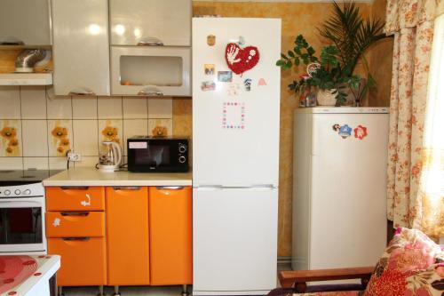 a kitchen with a white refrigerator and orange cabinets at Гірська Хатина in Mykulychyn