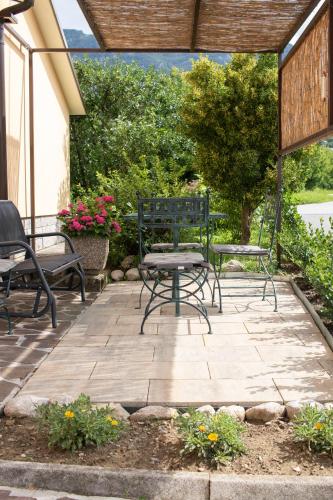 a patio with chairs and a table and benches at Borea Rooms - Sobe Budanje in Vipava