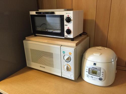 a microwave oven sitting on top of a refrigerator at Guest House Isa in Motobu