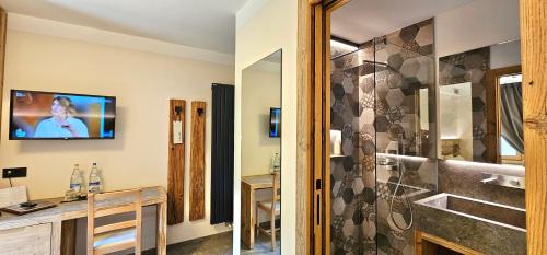 a bathroom with a shower and a television on the wall at Albergo Alpenrose in Livigno