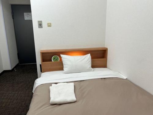 a bed in a room with a white pillow on it at Hotel Royal Oak Gotanda in Tokyo