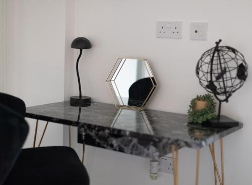 a table with a mirror and a lamp on it at Heathrow Haven in Yiewsley