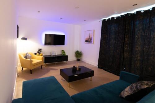 a living room with a blue couch and a table at Heathrow Haven in Yiewsley