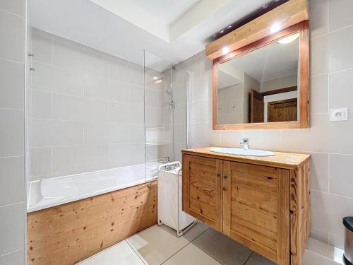 une salle de bain avec un lavabo, une baignoire et un miroir dans l'établissement Chalune - appartement - 8pers- centre, aux Gets