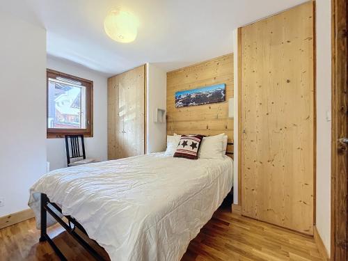 une chambre avec un grand lit avec un mur en bois dans l'établissement Chalune - appartement - 8pers- centre, aux Gets