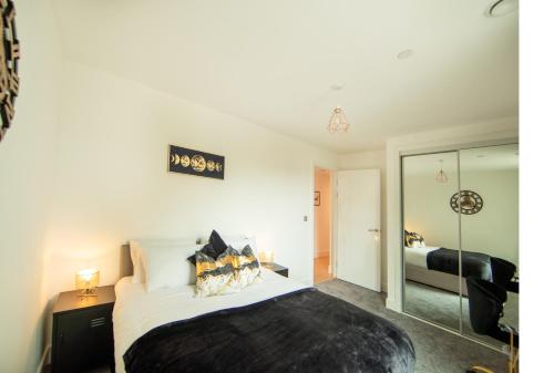 a bedroom with a large bed and a mirror at Heathrow Haven in Yiewsley
