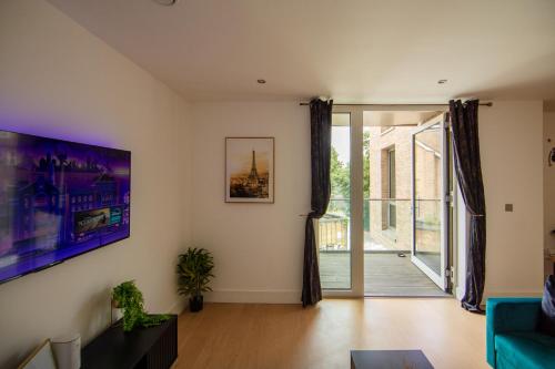 a living room with a blue couch and a sliding glass door at Heathrow Haven in Yiewsley