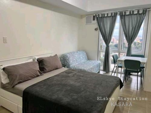 a bedroom with a bed and a chair and a table at Kasara Urban Residences - Cozy Studio Unit in Manila