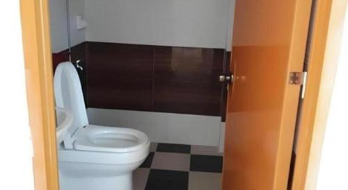 ein Badezimmer mit einem weißen WC und einem karierten Boden in der Unterkunft Gravino Pension House in Daanglungsod