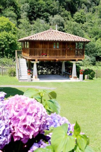 a large wooden gazebo in a park with purple flowers at Casa con Jardín y Barbacoa en Llanes – Molinin in Villanueva de Ardisana