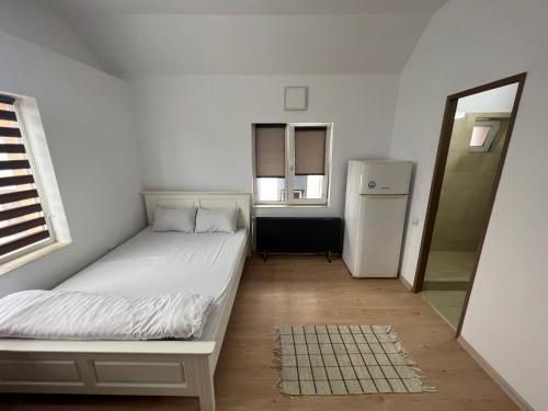 a small bedroom with a bed and a refrigerator at Compact House in Cluj-Napoca