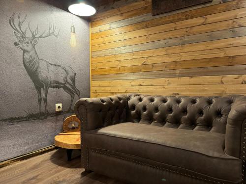 a living room with a leather couch and a deer mural at The Forest Villa Borovets by BookVillaBG in Borovets