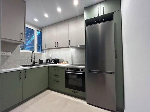 una cucina con mobili bianchi e un frigorifero in acciaio inossidabile di Urban Escape ad Atene