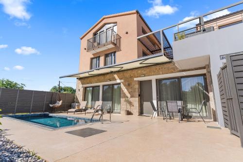 a villa with a swimming pool and a house at Argeno Suites Lefkada in Lefkada Town
