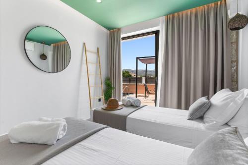 a bedroom with two beds and a mirror and a balcony at Argeno Suites Lefkada in Lefkada Town