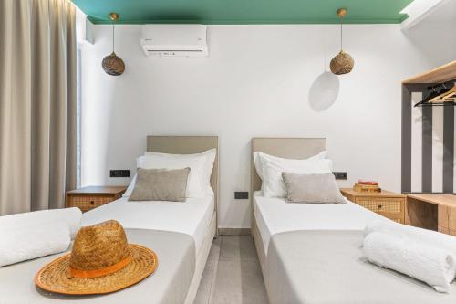 two beds in a room with a hat on top at Argeno Suites Lefkada in Lefkada Town
