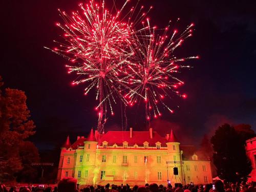 a castle with fireworks in front of a building at Le Logis Cantilien Lamorlaye-Chantilly in Lamorlaye