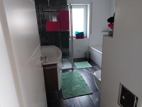 a bathroom with a sink and a shower with green mats at Ferienwohnung Josy in Memmelsdorf