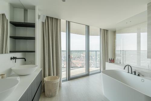 a white bathroom with two sinks and a large window at Enso District Residences in Knokke-Heist