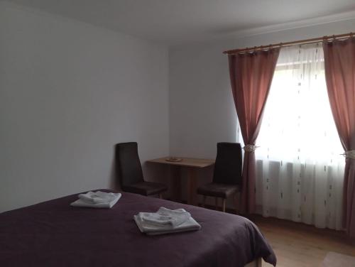 a bedroom with a bed and two chairs and a window at La Lacuri in Sovata
