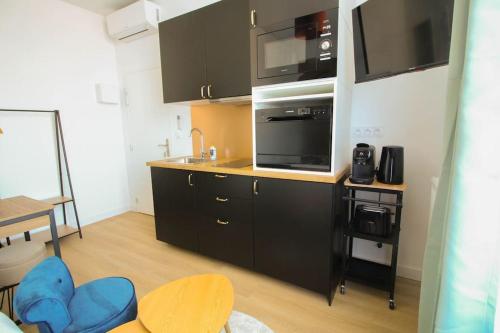 a kitchen with black cabinets and a microwave at G3 Studio Climatisé Centre Angouleme in Angoulême