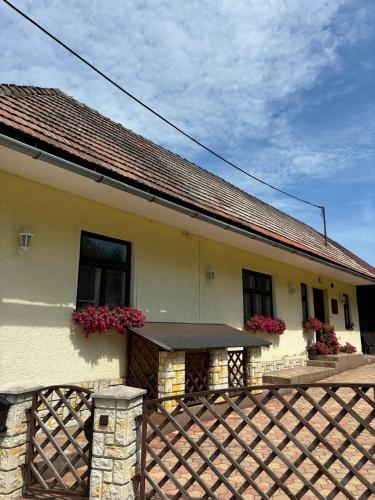 a house with flowers on the windows and a fence at Pobytový domček Studničná in Komjatná