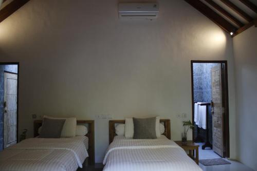 two beds in a room with two windows at Oemau Bungalow in Nembrala