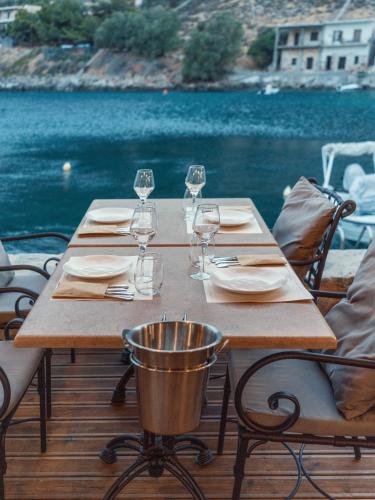 a wooden table with wine glasses and plates on it at KaSeas Boutique Hotel in Gerolimenas