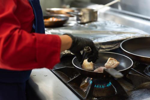 a person is cooking food in a pan on a stove at hôtel TY RU in Riec-sur-Bélon