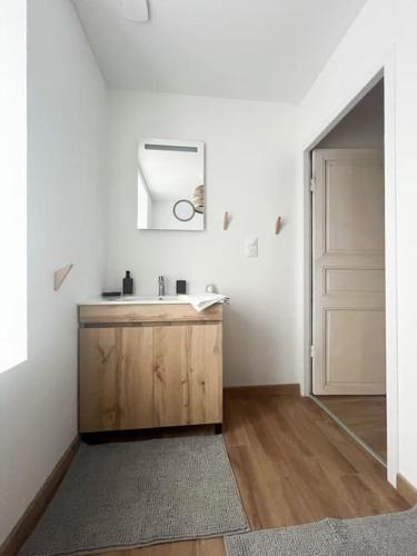 La salle de bains est pourvue d'un lavabo, d'un miroir et d'une porte. dans l'établissement Jolie maison entièrement rénovée proche du bourg et des plages, à Landéda