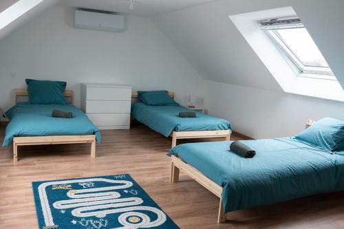 Cette chambre comprend 3 lits et un tapis. dans l'établissement Jolie maison entièrement rénovée proche du bourg et des plages, à Landéda