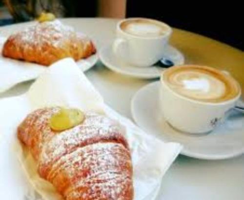 a table with two plates of pastries and cups of coffee at Valery AffittaCamere in Capannori