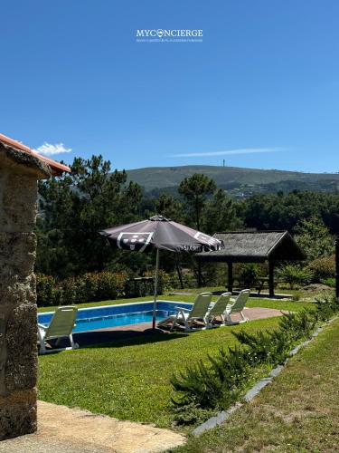 an umbrella and chairs next to a swimming pool at Vista Verde Lodge in Vale de Cambra