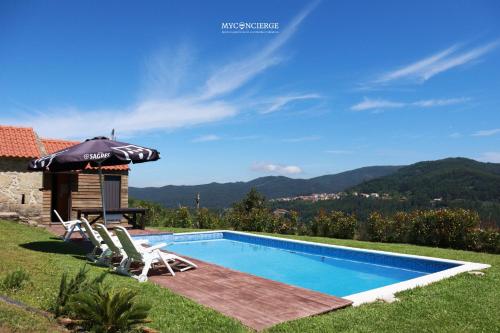 a villa with a swimming pool and an umbrella at Vista Verde Lodge in Vale de Cambra