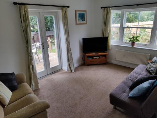 a living room with a couch and a flat screen tv at The Old Rope Works in Woburn Sands