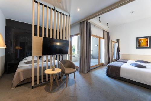 a hotel room with a bed and a table and a chair at Hotel Salona Palace in Solin