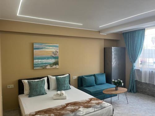 a bedroom with a bed and a blue chair at Стаи за гости Бела in Ahtopol