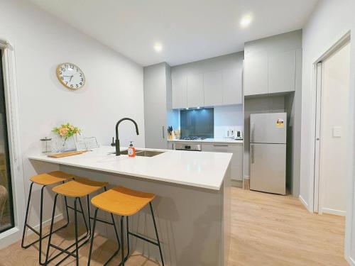 a kitchen with a sink and a counter with stools at Modern & Stylish 3 Bedroom at lowerhutt in Lower Hutt