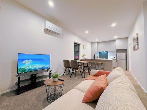 a living room with a couch and a flat screen tv at Modern & Stylish 3 Bedroom at lowerhutt in Lower Hutt